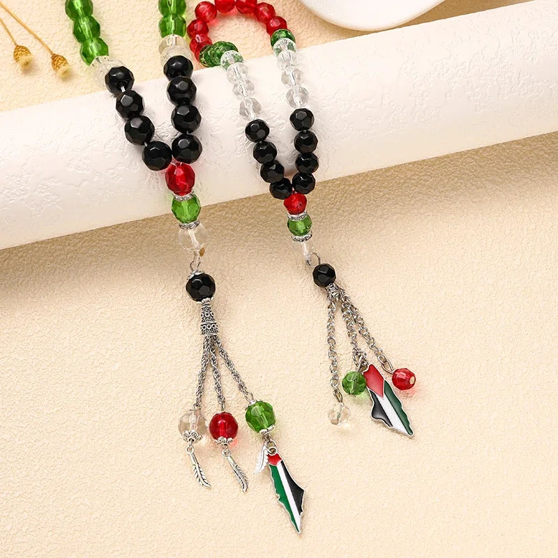 Ein Set Gebetsperlenarmband mit grünen, schwarzen und roten Perlen und palästinensischen Flaggenmotiven.