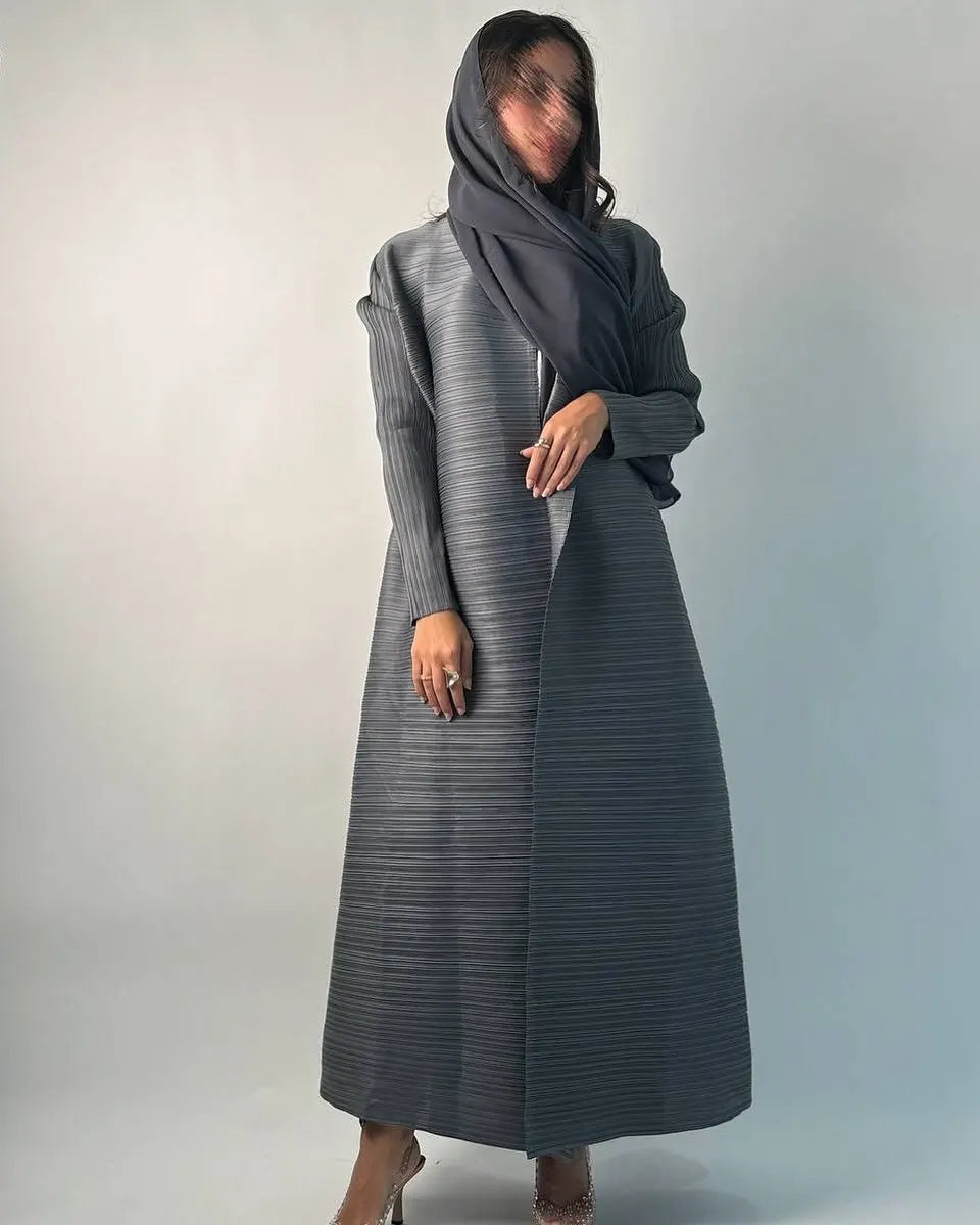 Una mujer vistiendo un cárdigan abaya plisado largo a rayas grises y un pañuelo negro para la cabeza.
