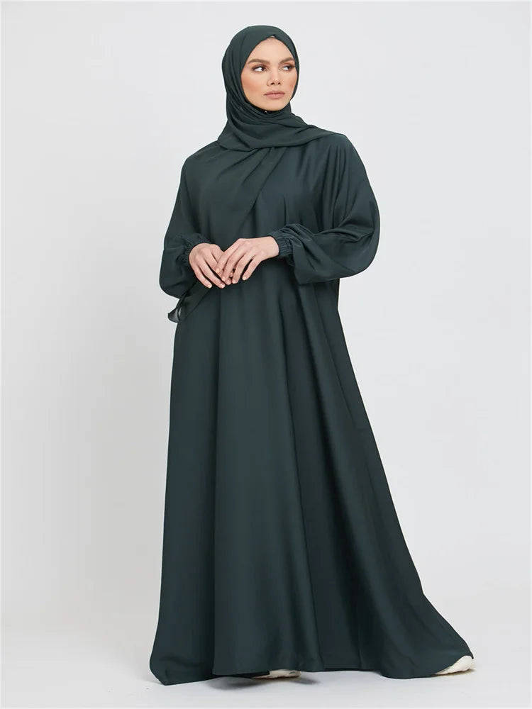 Eine Frau trägt ein dunkelgrünes marokkanisches Kaftan-Abaya und einen passenden Hijab.