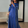 Una mujer modela un vestido abaya de satén azul real con vuelo en un estudio.