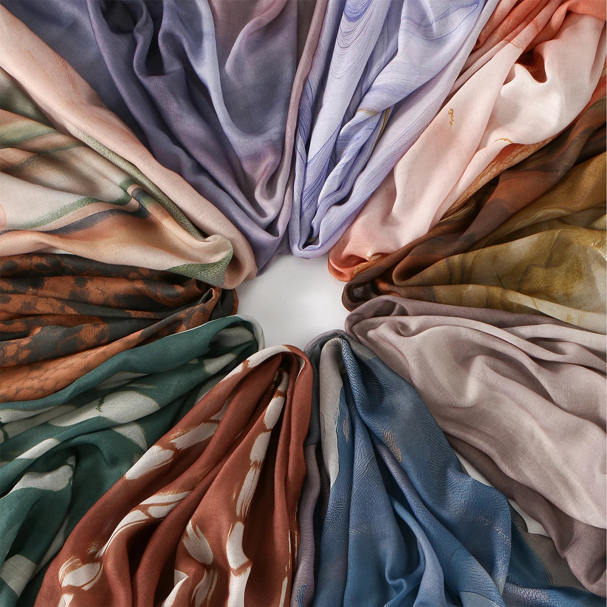 Eine Sammlung drapierter, fließender Stoffschals in gedämpften Tönen wie Beige, Lila, Pink und Braun.