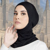 Eine Frau trägt eine schwarze, dehnbare Baumwoll-Hijab-Kappe und blickt direkt in die Kamera.