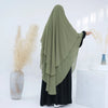 Eine Frau mit einem fließenden olivgrünen Chiffon-Niqab und schwarzer Kleidung vor weißem Hintergrund.