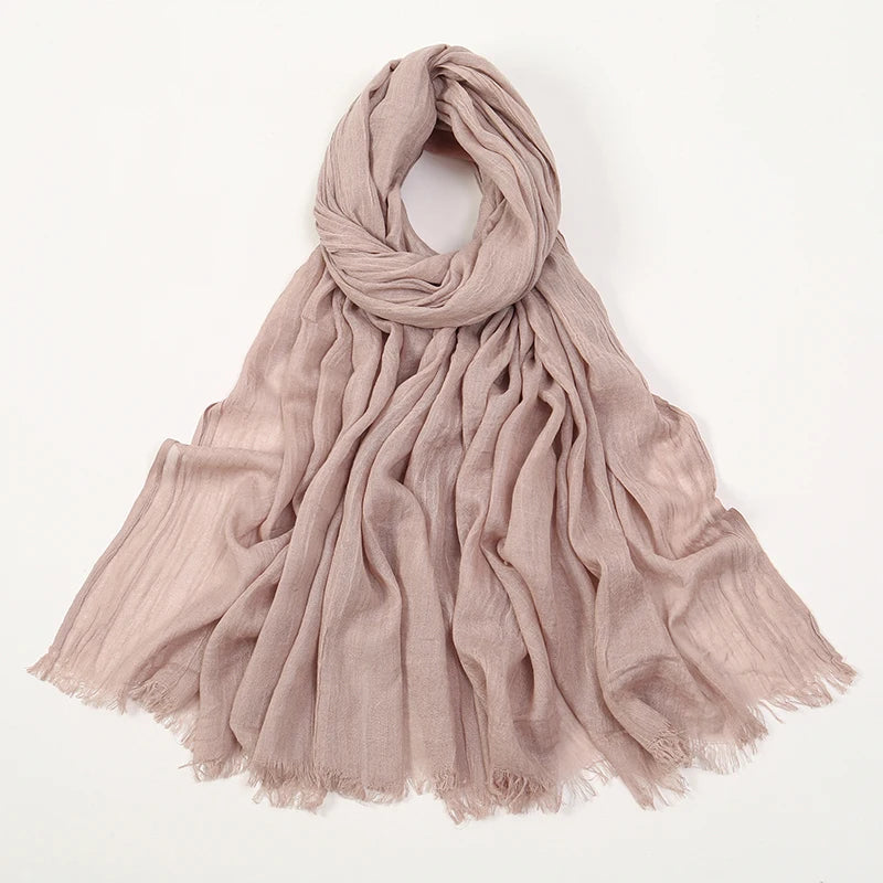 Pañuelo modal de bambú beige claro y fluido, drapeado alrededor del cuello.