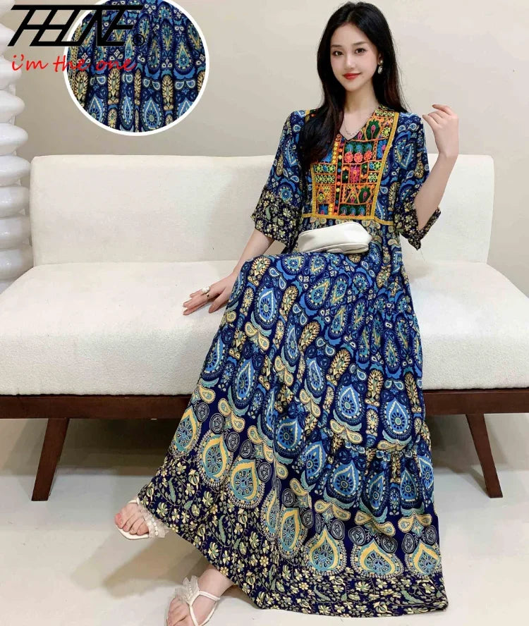 Eine Frau modelliert ein blau-gelbes, besticktes Boho-Maxikleid mit goldenen Akzenten.