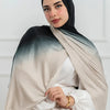 Una mujer vistiendo un pañuelo de hijab de algodón degradado doble cara en tonos beige y gris.
