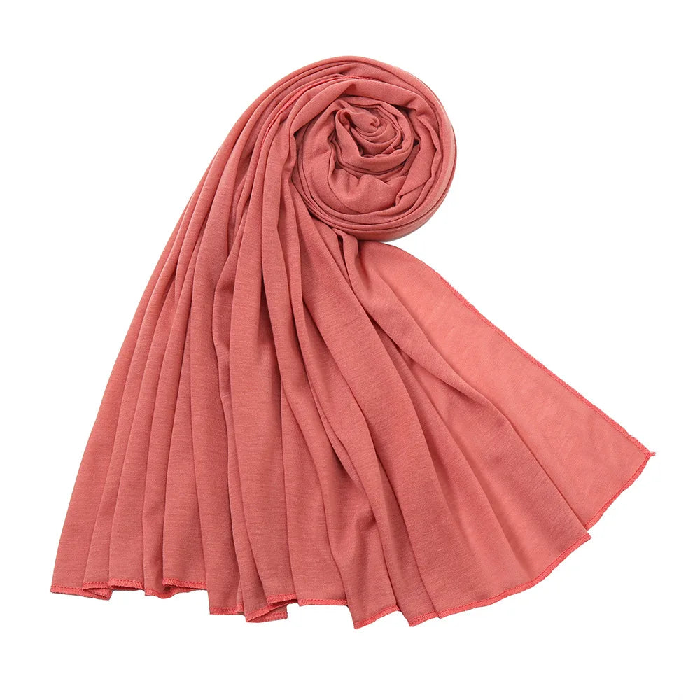 Foulard hijab en jersey de coton rose corail roulé, drapé élégamment.