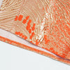 Close-up of an orange and gold satin abaya kaftan fabric with intricate patterns.