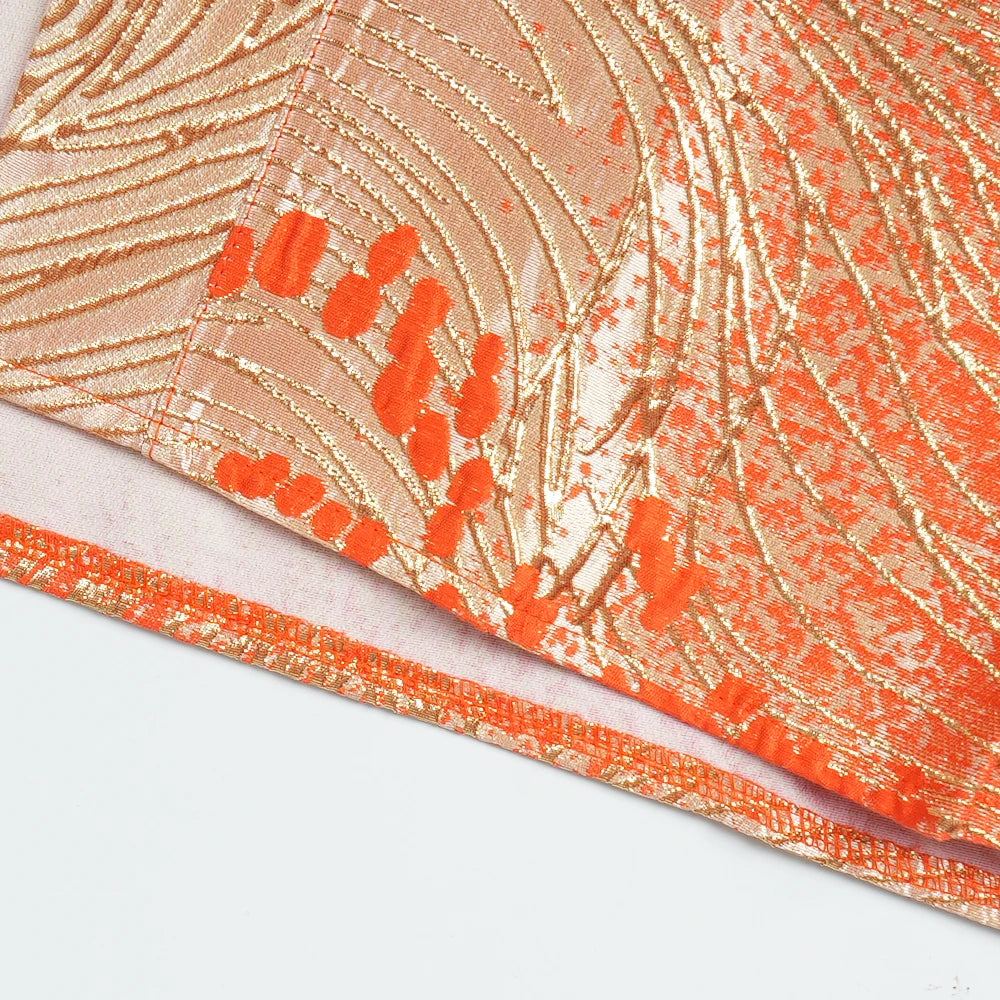 Close-up of an orange and gold satin abaya kaftan fabric with intricate patterns.