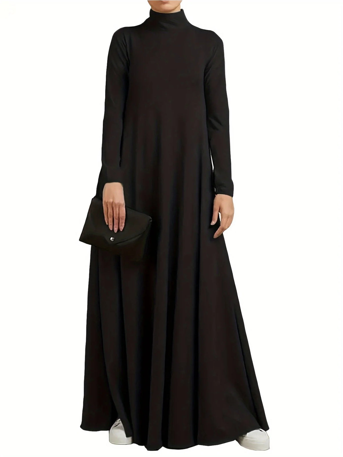 Une femme portant une longue robe ample noire et tenant une pochette noire.