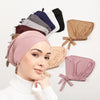 A woman models a pink inner hijab cap with a white turtleneck sweater, surrounded by various colored fabric options.