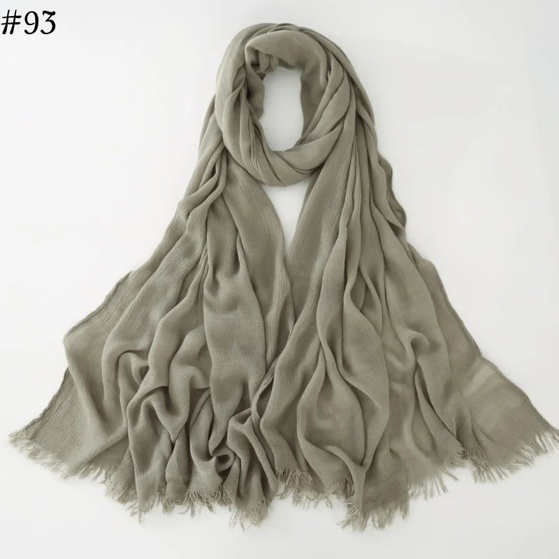 Un foulard hijab en coton viscose vert sauge, drapé et plié sur un fond blanc.