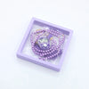 Purple prayer beads and digital counter bracelets displayed in a square clear box.