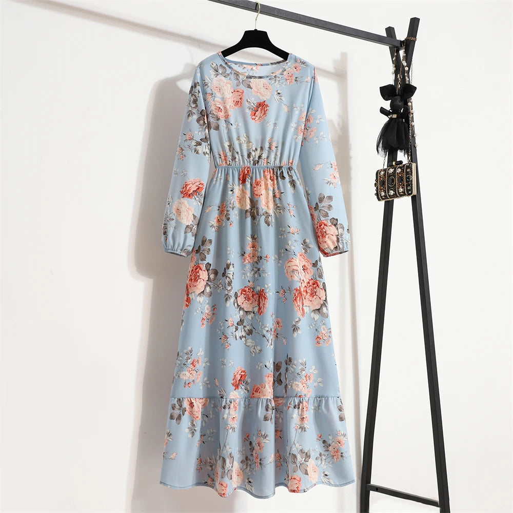 Hellblaue Maxi-Kleid mit Blumenmuster in Rosa- und Grüntönen, an einem schwarzen Kleiderständer hängt.