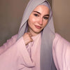 A woman wearing a lilac chiffon matching inner scarf set, featuring a pink top and a lilac hijab.