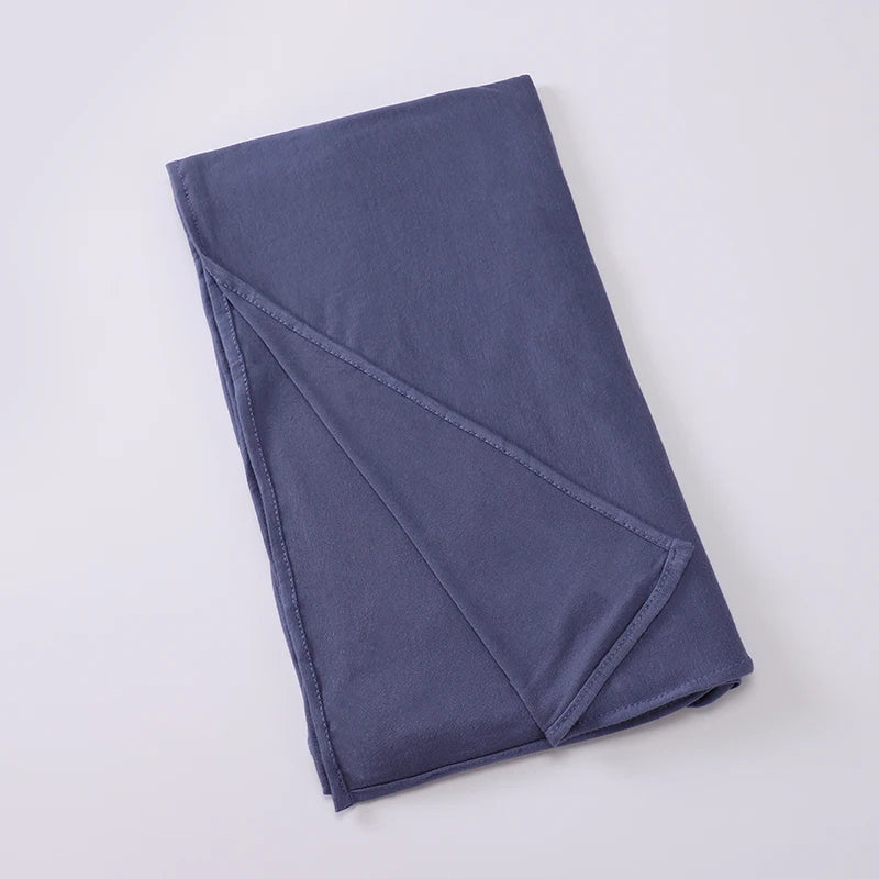 Écharpe instant hijab en jersey bleu marine et extensible, pliée et posée sur une surface gris clair.