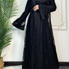 Une femme portant un ensemble abaya noir en dentelle avec des manches longues et une jupe ample.