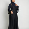 Eine Frau in einem schwarzen marokkanischen Kaftan-Abaya mit dunklem Hijab und goldenen Verzierungen.