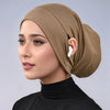 Eine Frau trägt eine beige Jersey-Baumwoll-Hijab-Kappe und ein schwarzes Rollkragenoberteil.