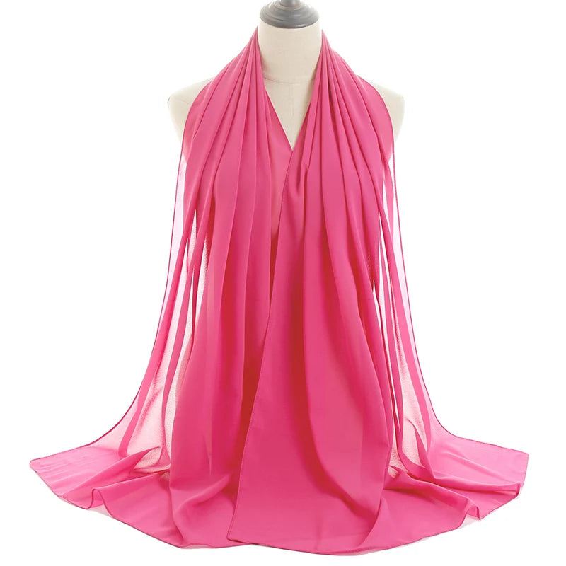Un pañuelo de chifón rosa brillante drapeado alrededor del cuello de un maniquí.