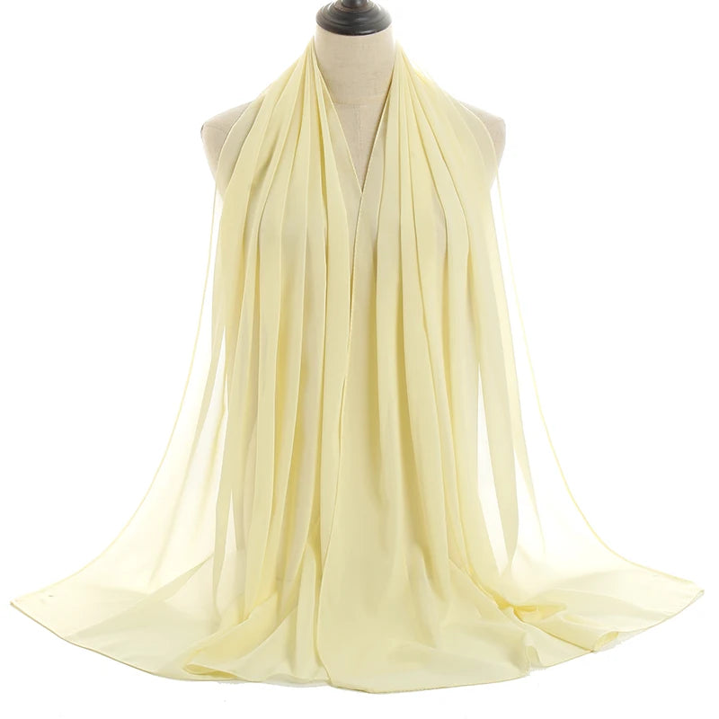 Un pañuelo de chifón amarillo pálido drapeado alrededor del cuello y los hombros de un maniquí.
