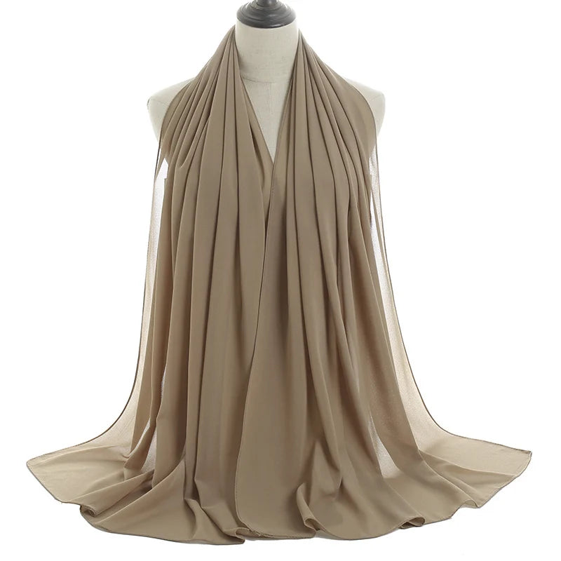 Un pañuelo de chifón beige drapeado alrededor del cuello y los hombros de un maniquí.