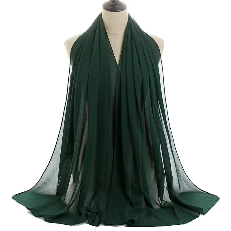 Un pañuelo de chifón verde esmeralda oscuro drapeado alrededor del cuello de un maniquí.