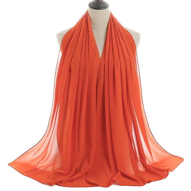 Bufanda de gasa naranja drapeada alrededor del cuello de un maniquí