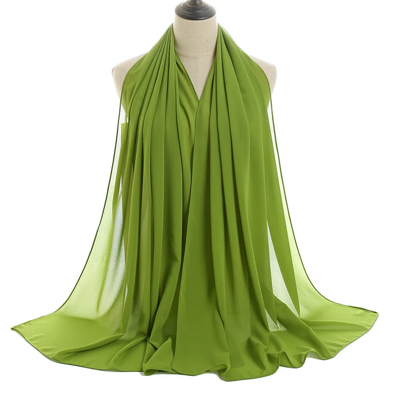 Un pañuelo de chifón verde lima fluído drapeado alrededor del cuello de un maniquí.