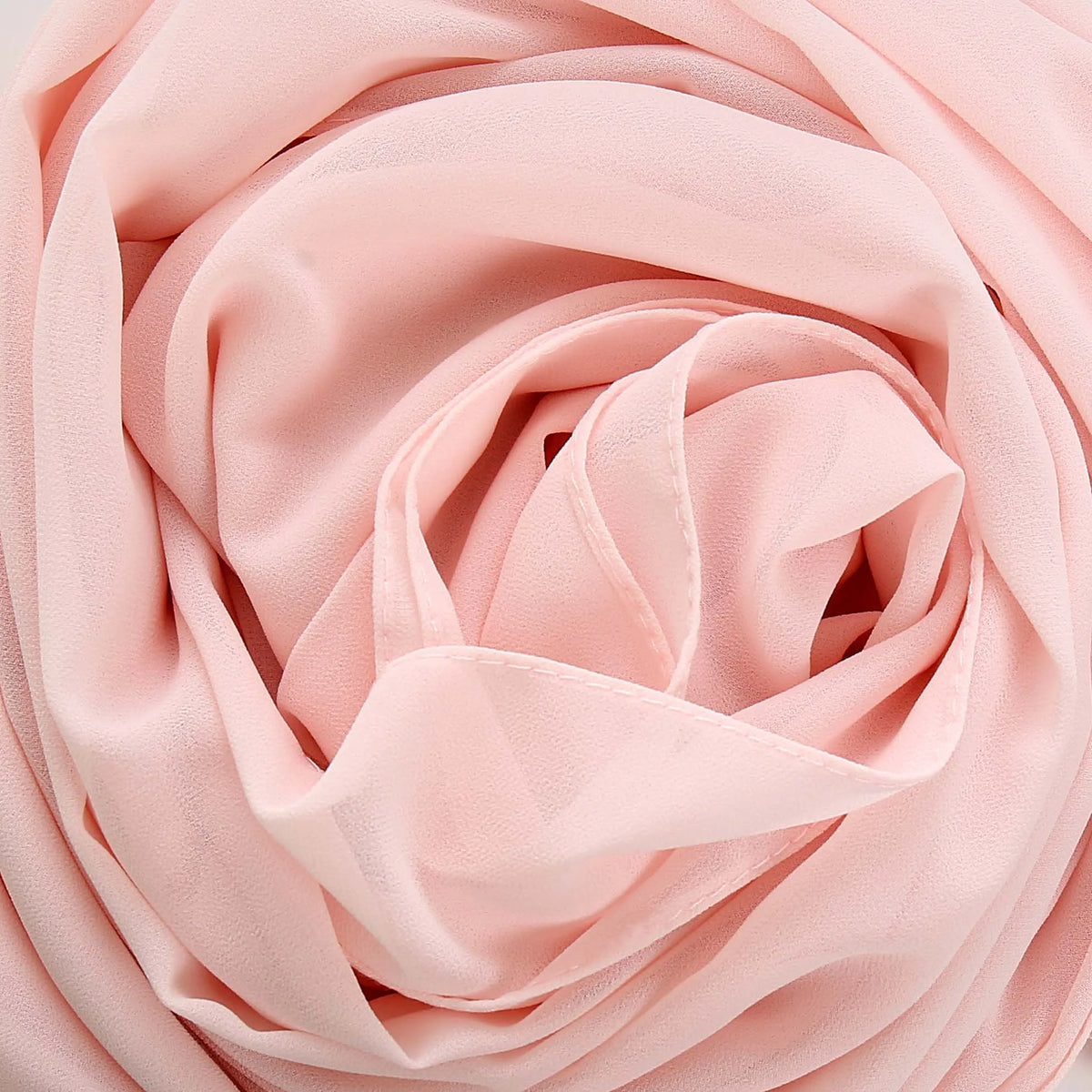 Primer plano de un pañuelo de chifón rosa suave, bellamente recogido y drapeado.