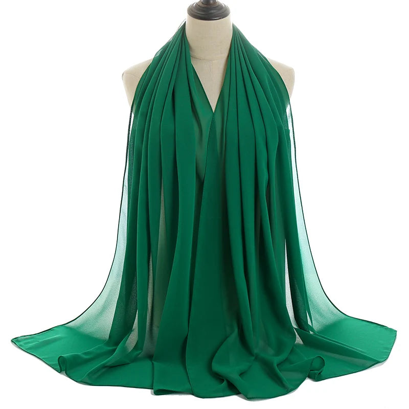 Un vibrante pañuelo de chifón verde esmeralda drapeado alrededor del cuello de un maniquí.