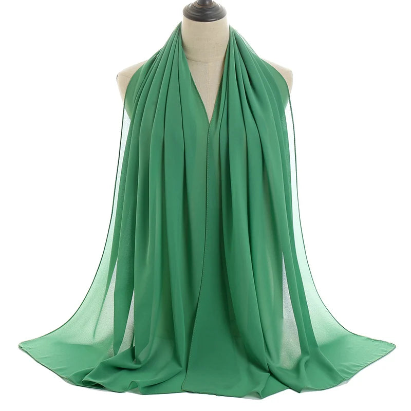 Un pañuelo de chifón verde esmeralda que cae alrededor del cuello de un maniquí.